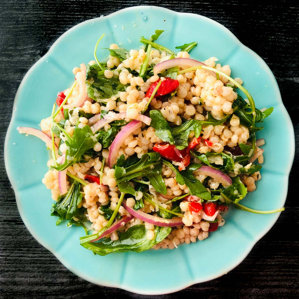 arugula couscous salad on an aqua plate