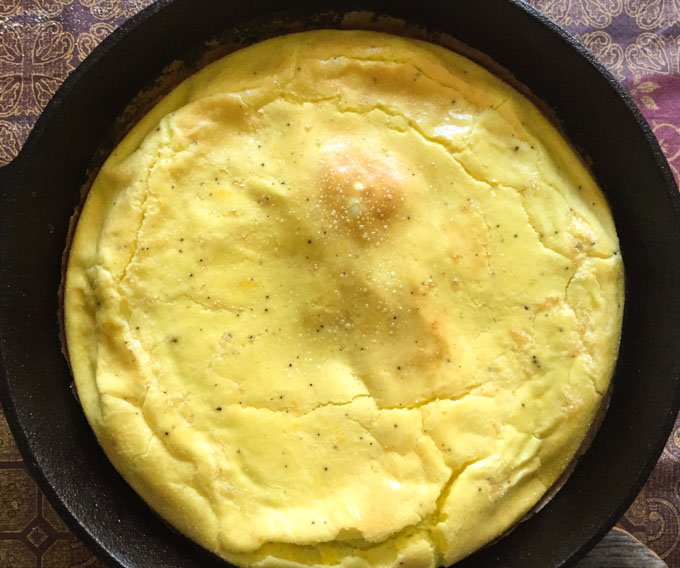 A cast iron skillet with cooked frittata base.
