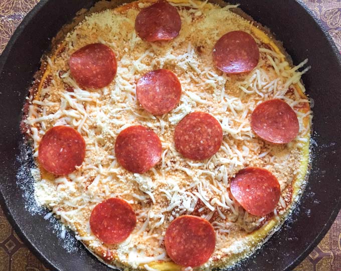 Cast iron skillet with frittata and raw cheese and pepperoni