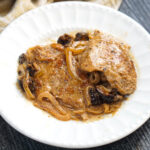 Closeup of a white plate with a serving of pork tenderloin with fig sauce.