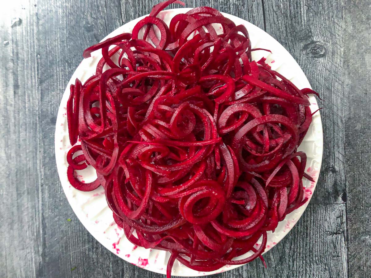white plate with raw beet noodles