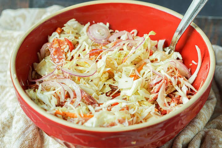 red bowl filled with antipasto keto cabbage salad with a beige tea towel 