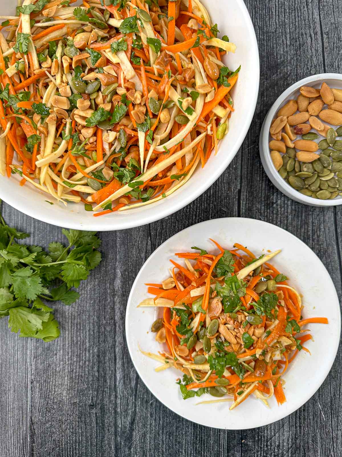 aerial view of white bowl and plate with Asian carrot salad with parsnips and fresh cilantro sprig