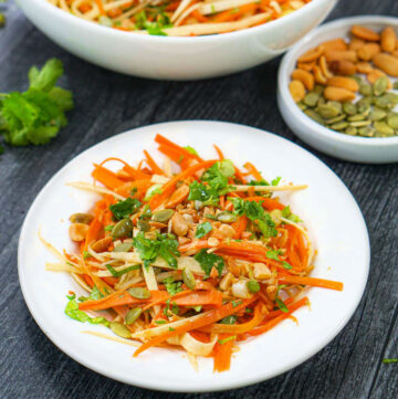white plate with crunchy Asian carrot salad with parsnips, peanut and seeds