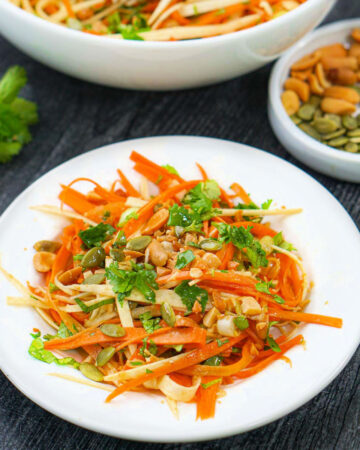 white plate with crunchy Asian carrot salad with parsnips, peanut and seeds