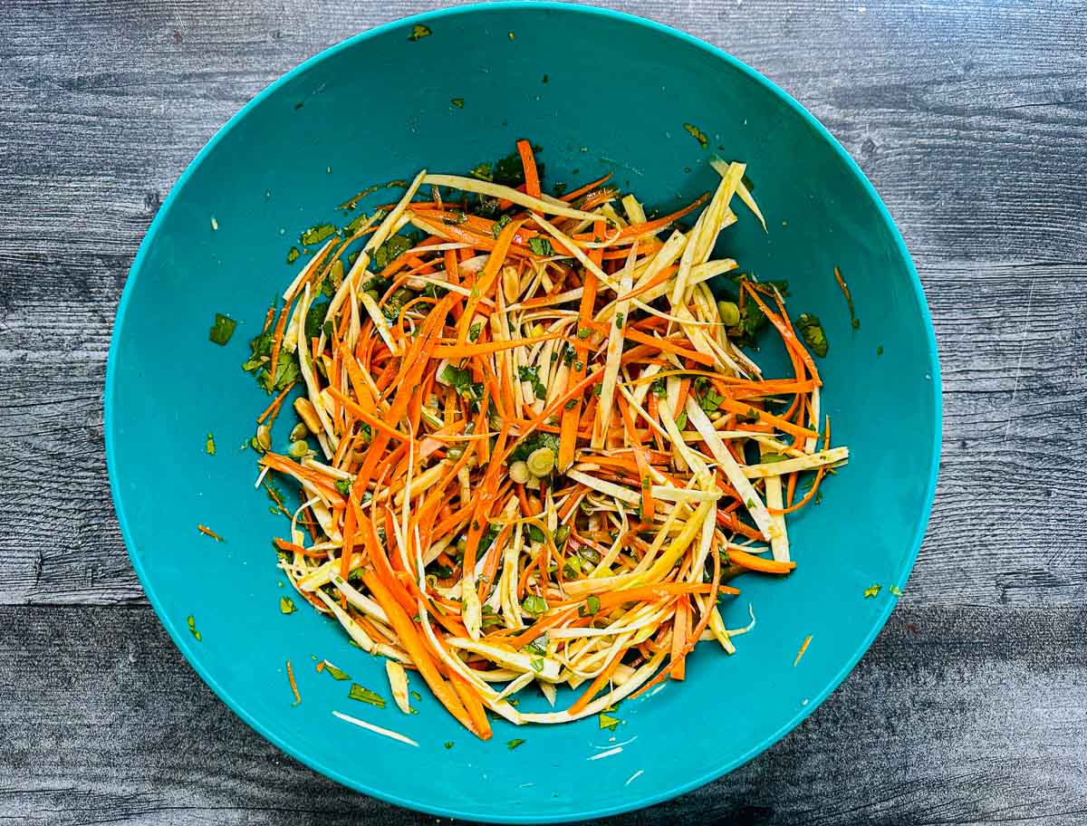 green bowl with veggie noodles tossed in dressing