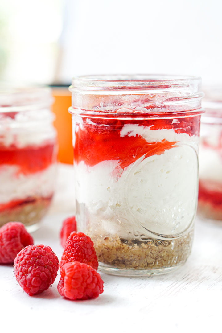 closeup of a glass jar with raspberry no bake keto cheesecake with fresh raspberries infant