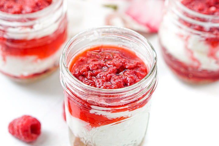 closeup of the top of a jar with no bake cheesecake showing the sugar free raspberry topping