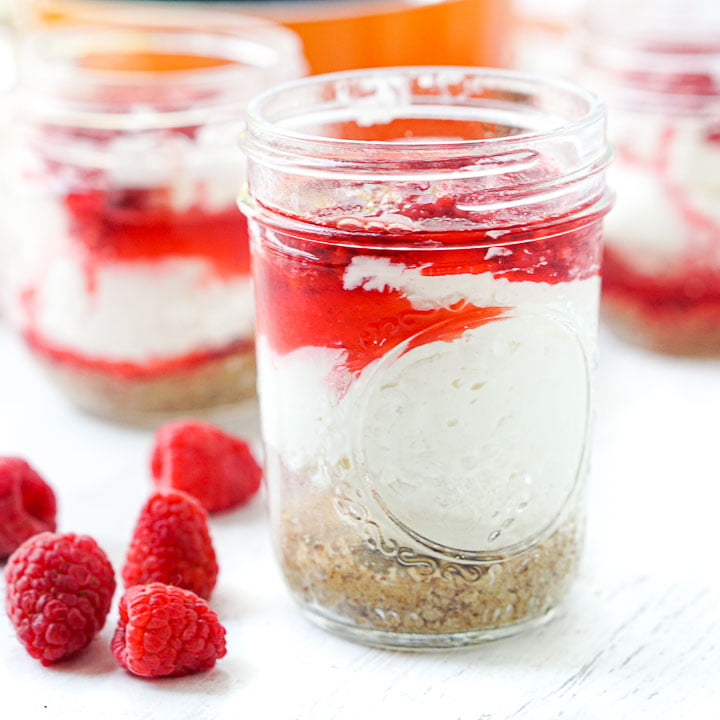 glass jar with raspberry no bake keto cheesecake and a few fresh raspberries