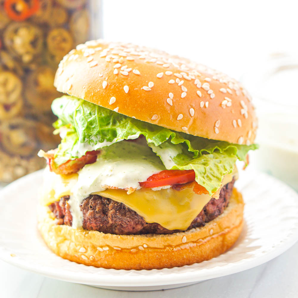 loaded burger with dripping jalapeno aioli burger sauce and sesame bun