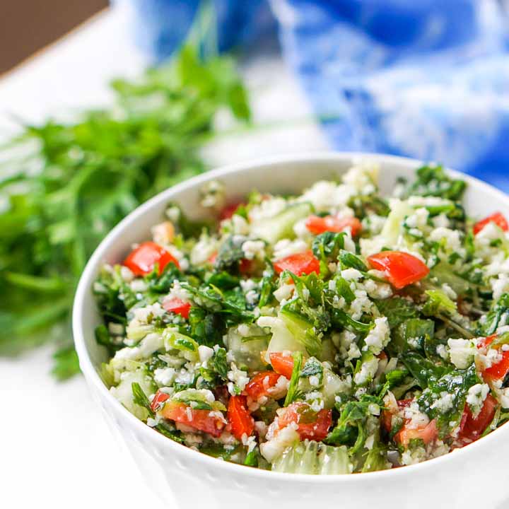 close up of gluten free cauliflower rice tabouli salad with parsley springs in background