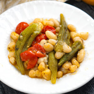 White dish with okra and tomatoes with beans.