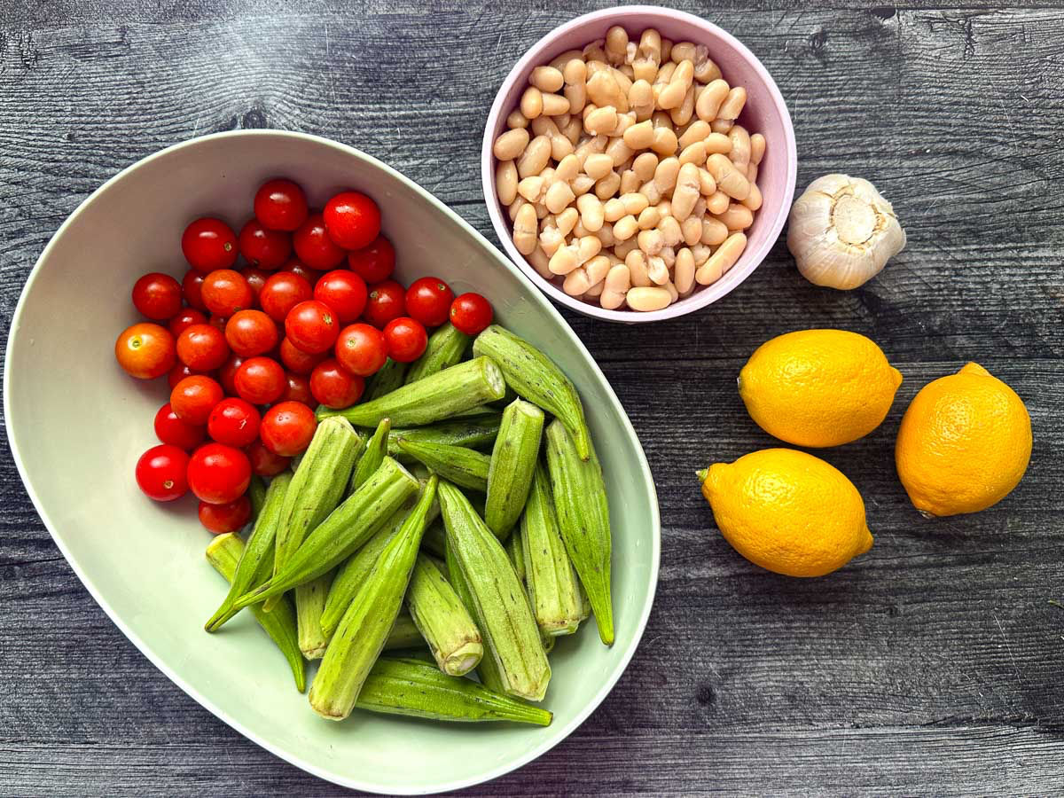 Recipe ingredients - cherry tomatoes, okra, fresh garlic, lemons and cannellini beans.