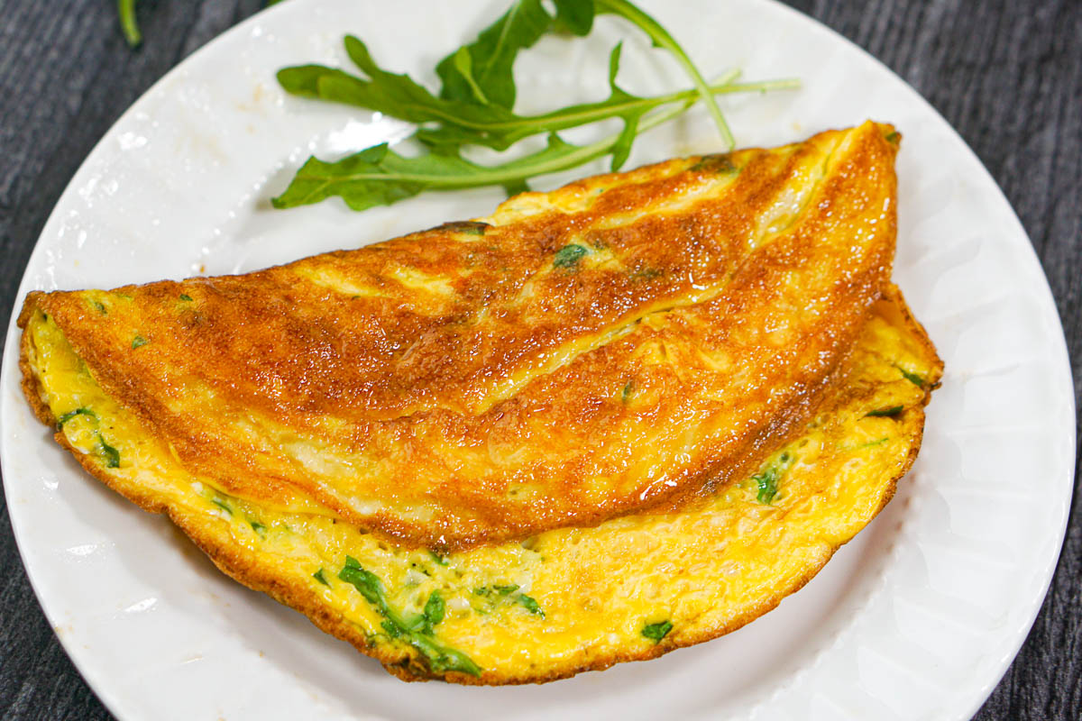 closeup of an arugula omelet on white plate