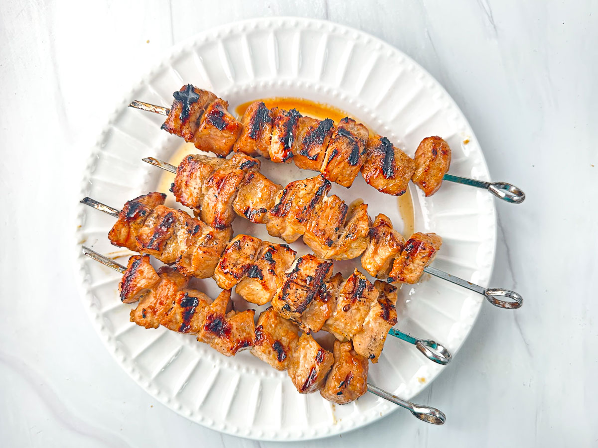 white plate with finished marinated pork kebabs on white plate
