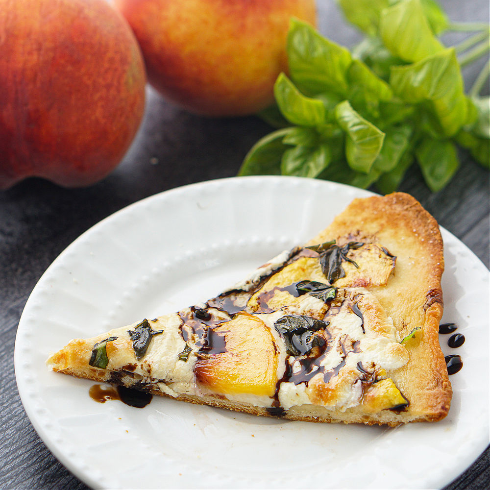 closeup of a piece of peach & basil naan bread pizza on a white plate