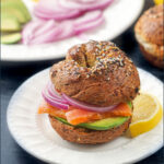closeup of a smoked salmon avocado bagel sandwich with text