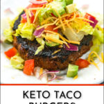 closeup of a keto taco burger with lettuce, onions, avocado and tomatoes on top and a pan and fixing in the background with text
