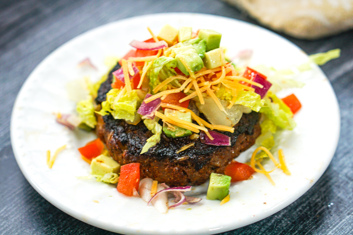 closeup of a the finished keto taco burger with lots of Mexican toppings