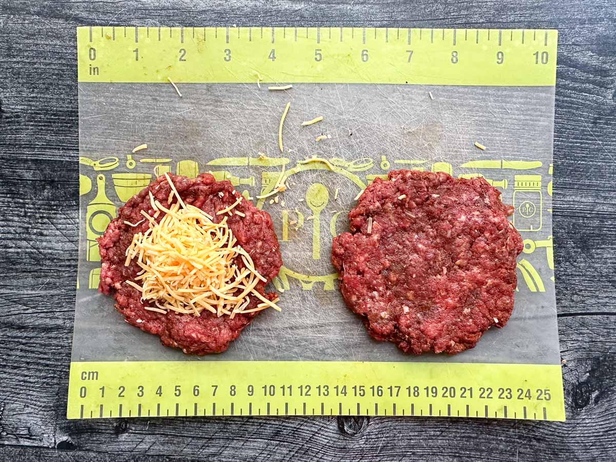 a burger split in half with cheddar cheese sprinkled in the middle