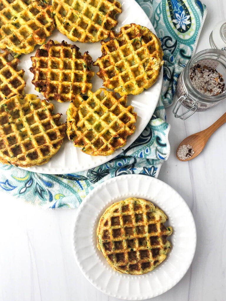 aerial view of large and small white plates with low carb veggie waffles and a jar of salt