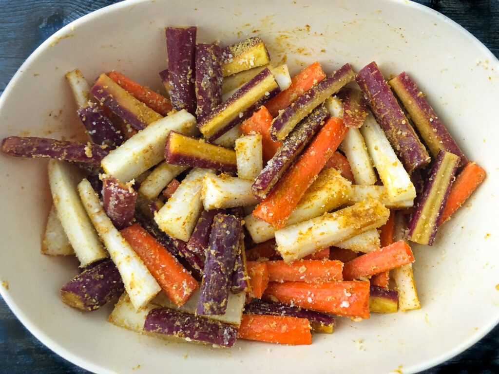 bowl with raw carrots covered in curry spices and coconut oil
