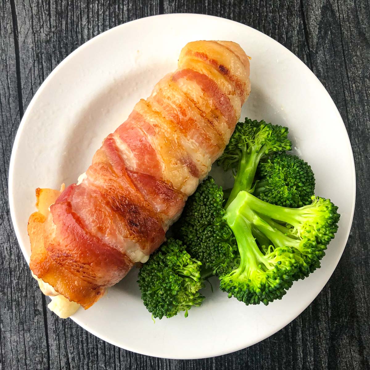 white plate with bacon wrapped chicken and broccoli