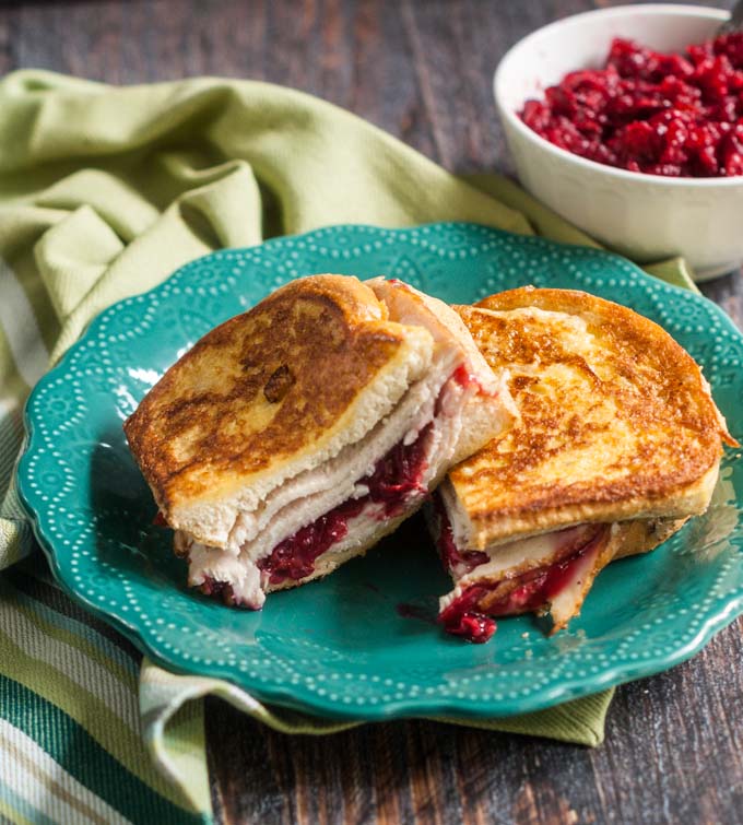 leftover turkey Cristo sandwich with a bowl of cranberry sauce in the background and a green tea towel
