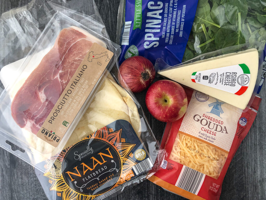 ingredients to make naan flatbreads- naan, prosciutto, apples, red onions, gouda and asiago cheese and spinach