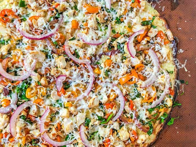 closeup of a low carb pizza made with cauliflower crust, vegetables and chicken