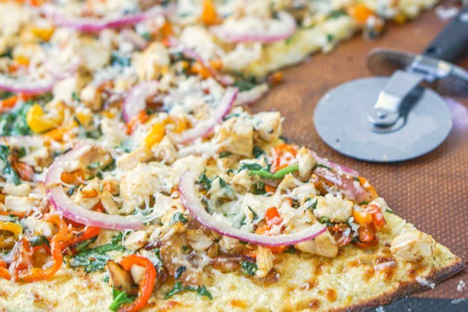closeup of chicken & vegetable keto pizza wit pizza cutter