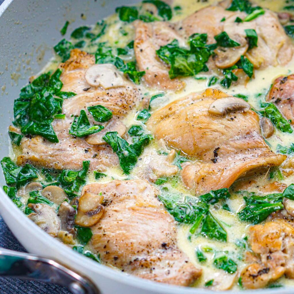 Closeup of a pan of keto creamy chicken and spinach with mushrooms skillet.