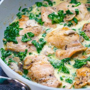 Closeup of a pan of keto creamy chicken and spinach with mushrooms skillet.