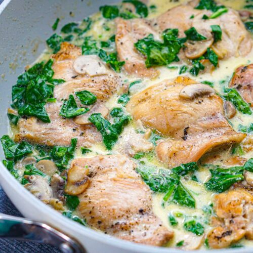 Closeup of a pan of keto creamy chicken and spinach with mushrooms skillet.