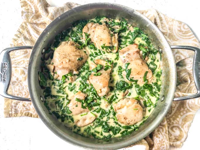 aerial view of low carb chicken dinner of chicken thighs, spinach and mushroom sauce with beige tea towel