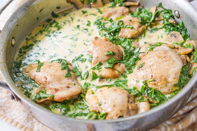skillet with chicken thighs in a low carb creamy spinach sauce