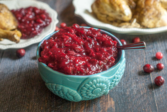 sugar free cranberry sauce in an aqua bowl with a few scattered raw cranberries