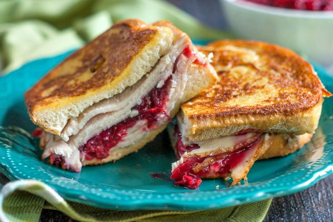 leftover turkey sandwich with cranberry sauce on green plate