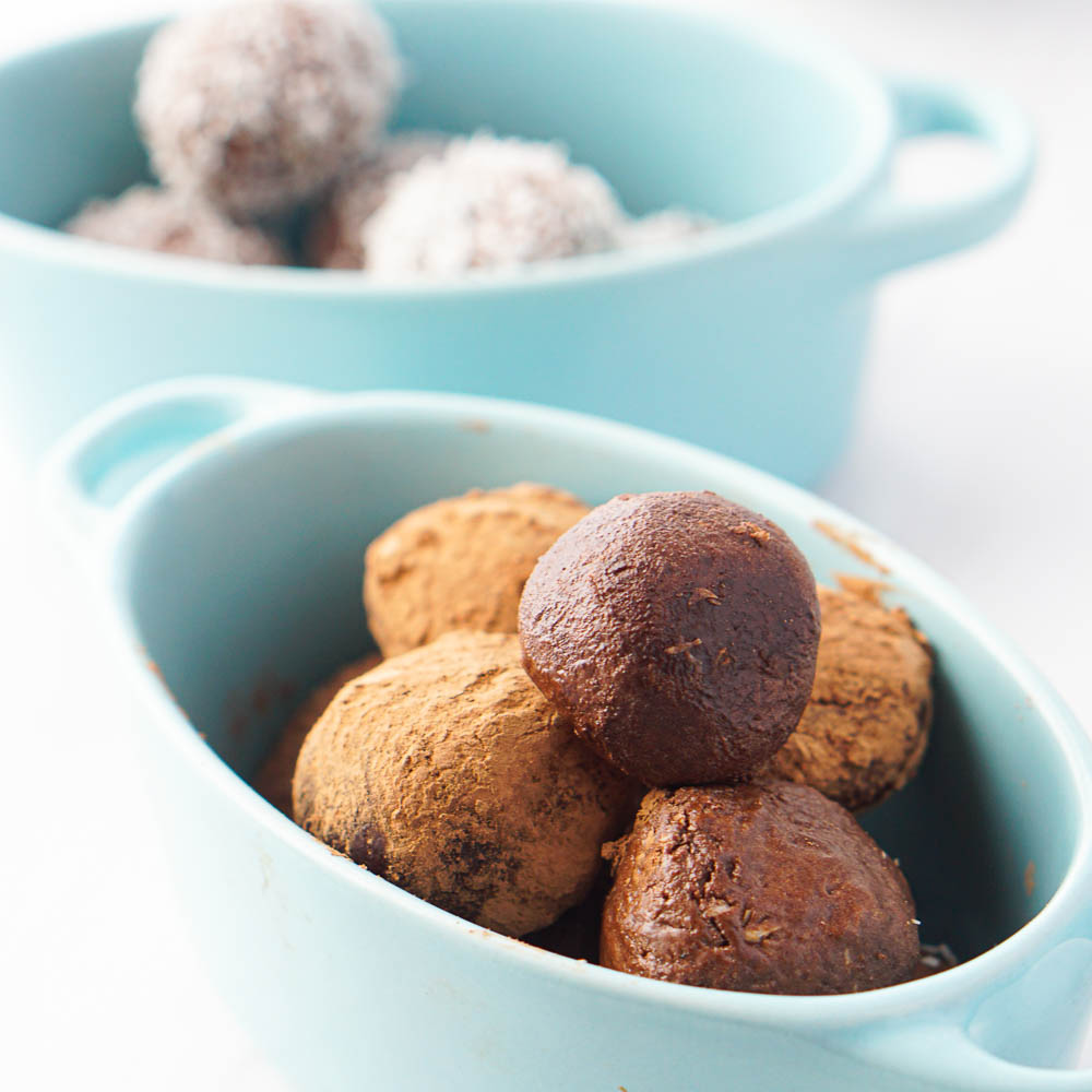 blue bowls with keto protein balls which are chocolate coconut flavored
