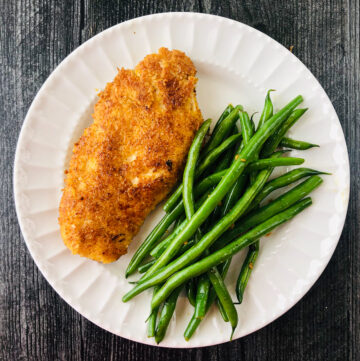 white plate with coconut chicken breast and green beans