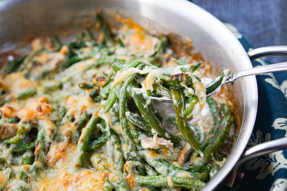 a spoonful of cheesy green beans out of the pan