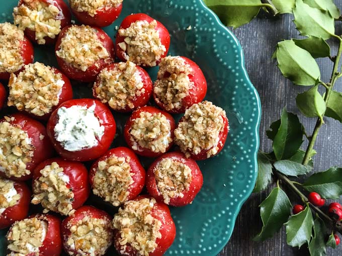 closeup of green plate with goat cheese stuffed pepper appetizer and a sprig of holly