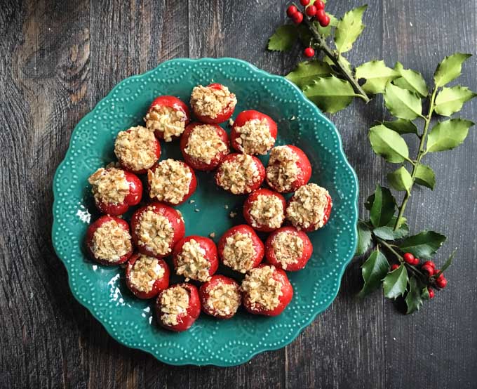 green plate with goat cheese stuffed pepper appetizer and a sprig of holly