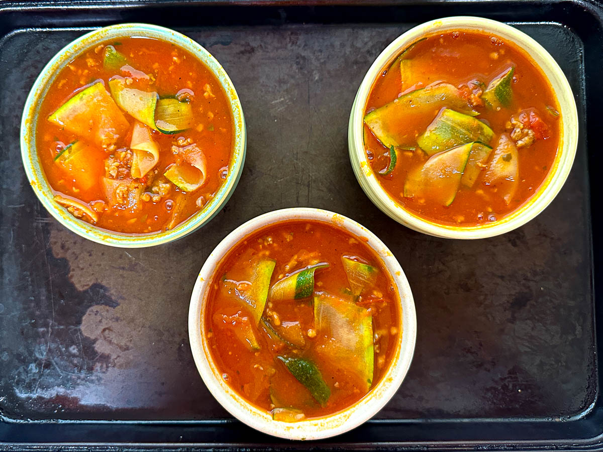 Baking sheet with 3 bowls of finished keto lasagna soup before adding cheese.
