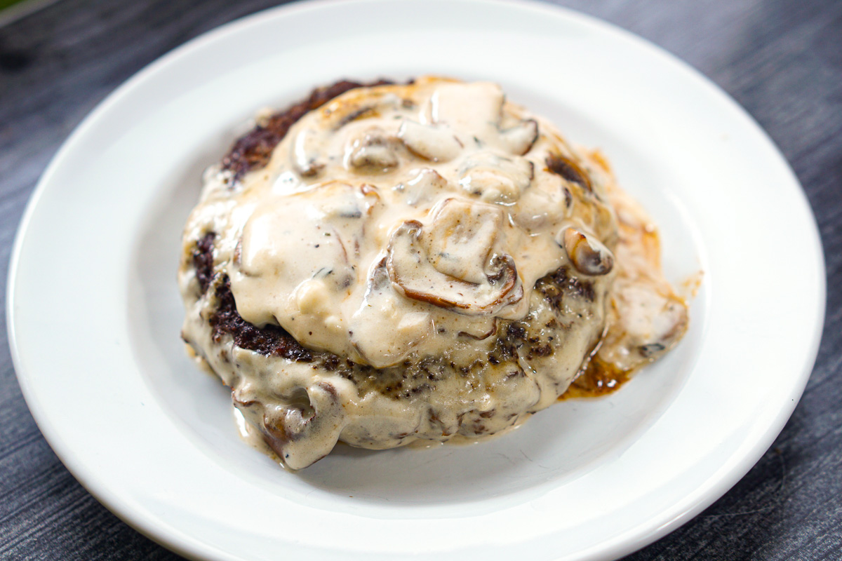 white plate with 1 burger with cheesy sauce