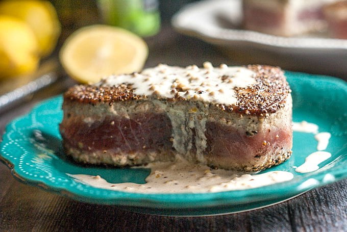 Closeup photo of tuna steak with sauce on a green dish.