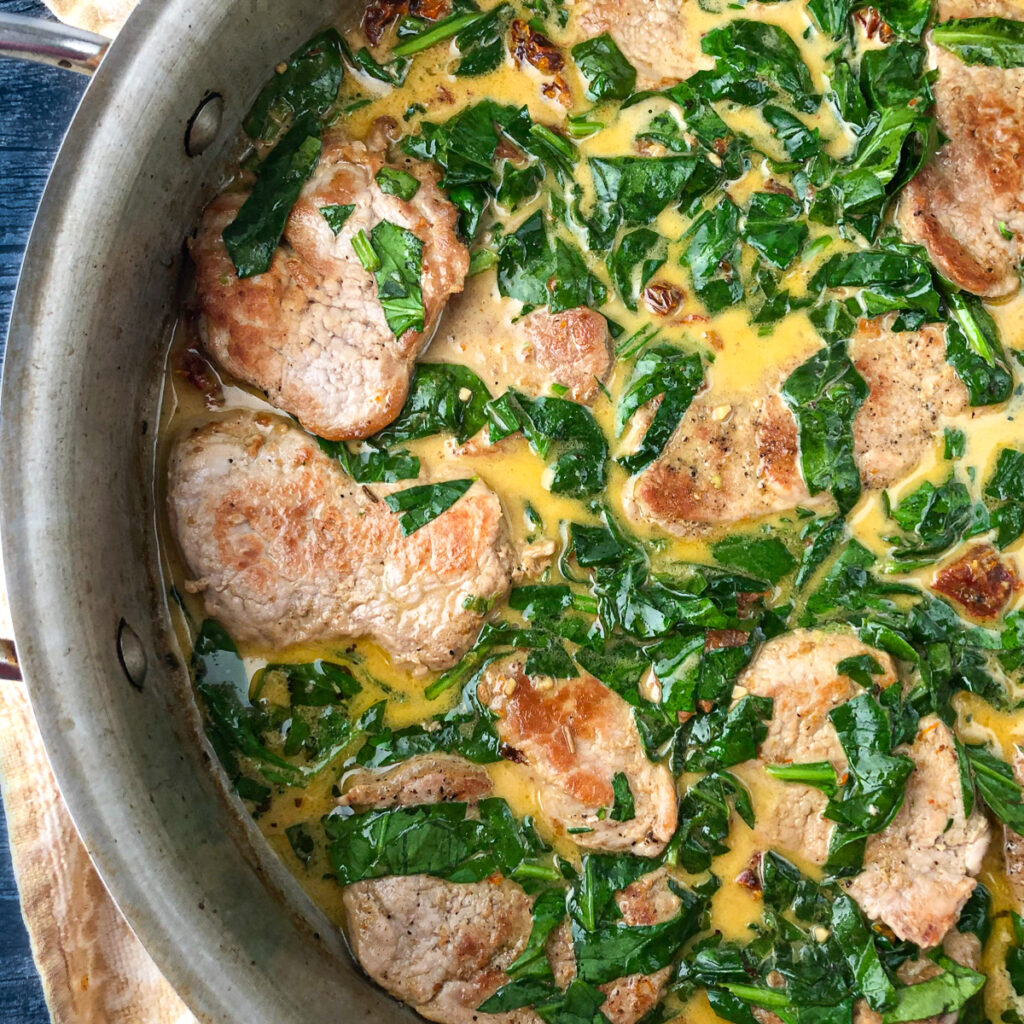 closeup of skillet with pork tenderloin with sun dried tomatoes and spinach