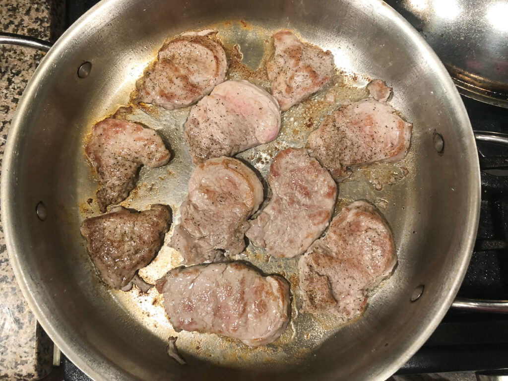 pan with browned pork tenderloin slices