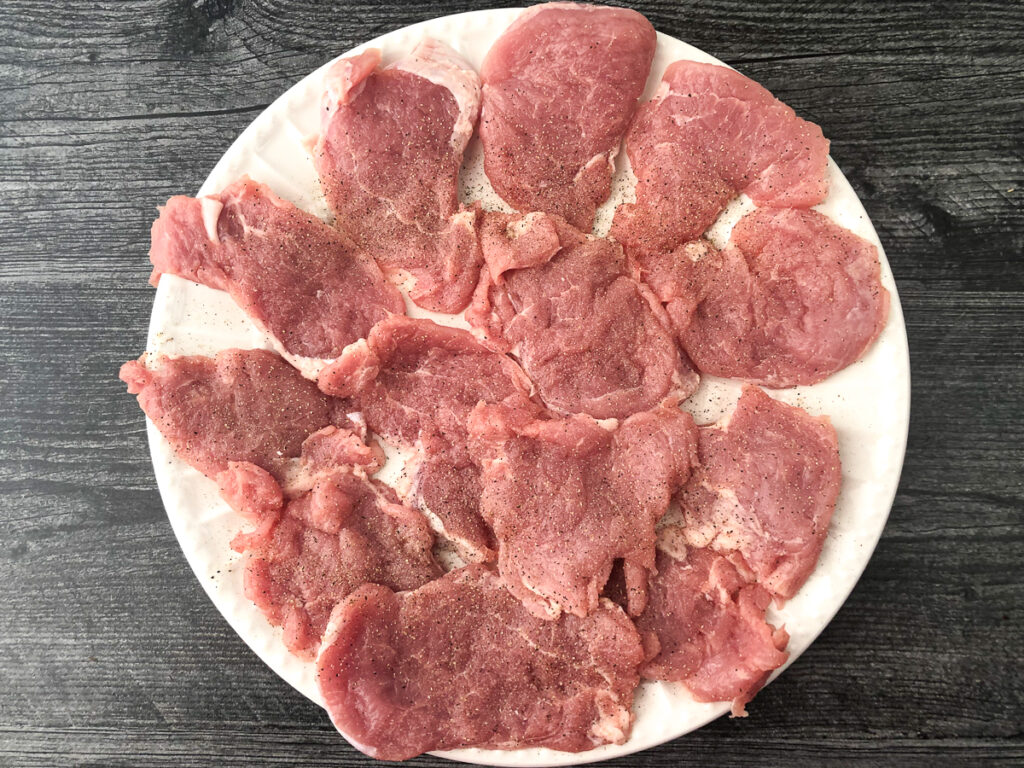 white plate with raw pieces of pounderd pork tenderloin slices