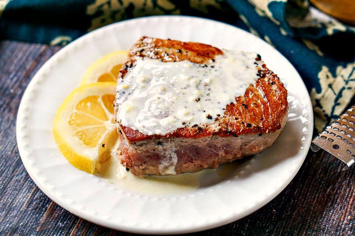 closeup of a white plate with a seared tuna steak with lemon dijon sauce on top
